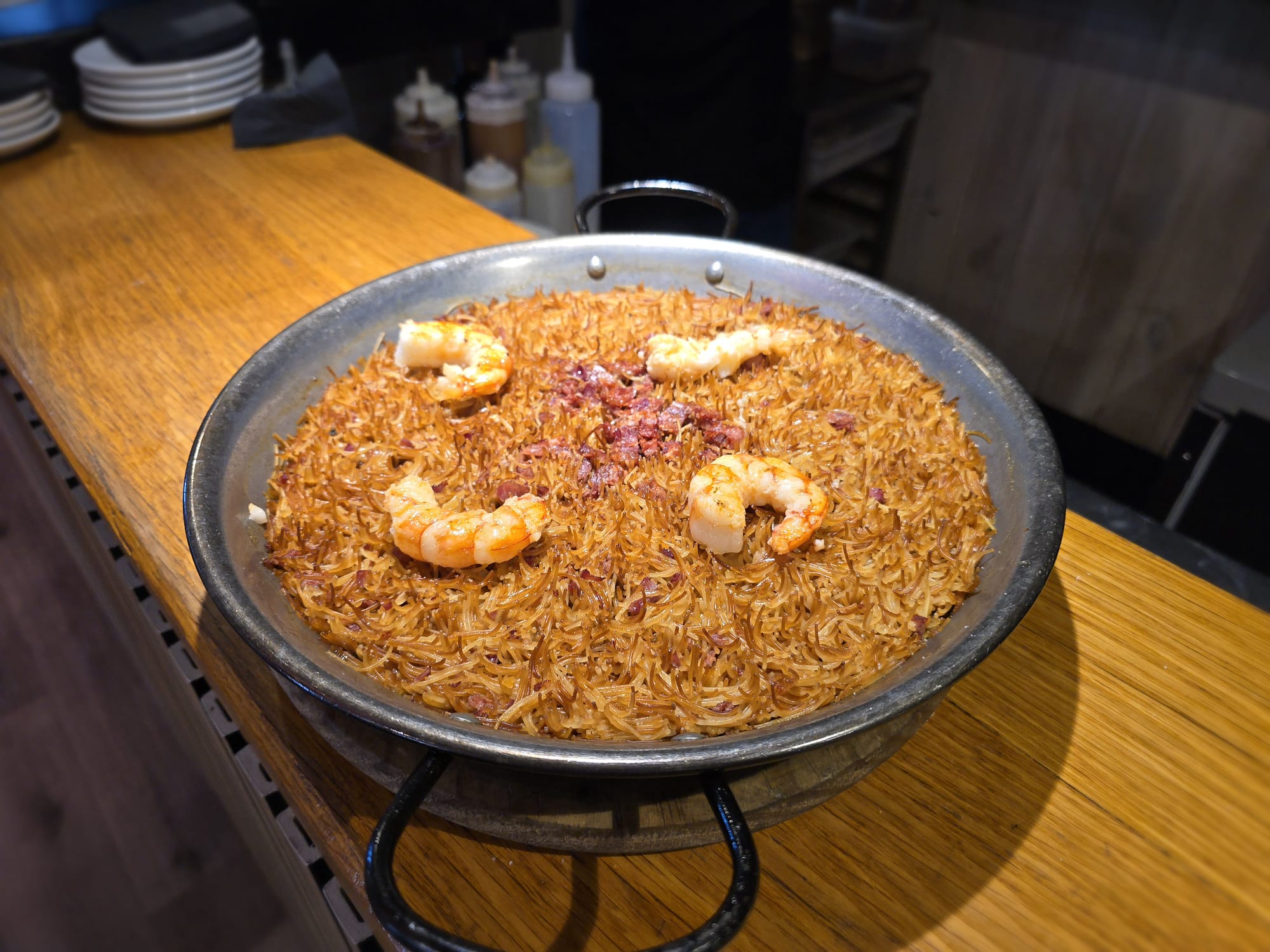 Plato de fideuá con fideos dorados, botillo desmenuzado y gambas, fusionando tradición y sabor. La mejor receta de fideuá con productos de León.